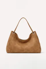 Cartera tipo hobo de gamuza color marrón, con diseño minimalista, asa única y detalles de argollas metálicas en los extremos.