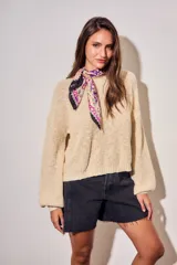 Sweater de tejido bouclé texturado color beige, con cuello redondo y mangas largas holgadas de corte amplio.