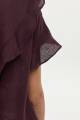 Blusa de lino color beige, de manga corta con volados, cuello redondo y espalda cruzada con volados.