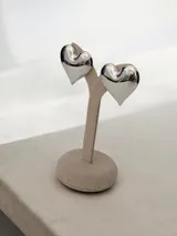 Aros tipo caravana con diseño de corazón inflado en acabado plateado brillante.