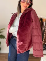 Campera de invierno color bordó, con cuerpo de pelo sintético tipo teddy y mangas acolchadas con diseño de bloques. Cuenta con capucha, cierre frontal y bolsillos laterales.