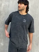 Remera gris con efecto gastado, corte oversize, mangas cortas y estampado en la espalda con el texto "SUPPLY GOODS DESIGNED IN PUNTA DEL ESTE".