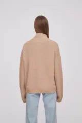 Sweater de tejido de punto en color beige, con cuello en V cruzado y mangas largas con puños ajustados.