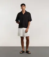 Camisa masculina blanca de lino, modelo boxy, con cuello bowling, manga corta y abotonado delantero.