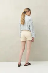 Short de tiro medio y calce ajustado, color blanco, con dobladillos en las piernas y cierre frontal con botón.