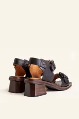 Sandalias de cuero negro con taco bloque de madera tallada, tiras con hebillas grandes y punta cuadrada.