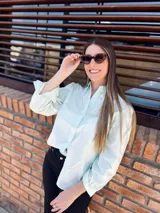 Camisa verde agua con cuello babero de puntilla blanca, mangas largas abullonadas con puños elastizados y cierre frontal con botones.