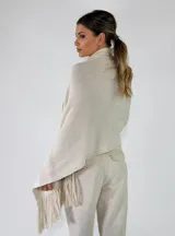 Pashmina de punto color beige con bordados sutiles y flecos largos en los bordes.
