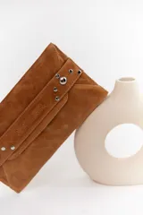 Sobre de cuero negro con solapa, cierre magnético y muñequera con tachas plateadas.