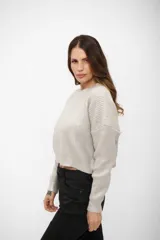 Buzo de tejido de punto con acabado brillante, cuello redondo, mangas largas y corte cropped.