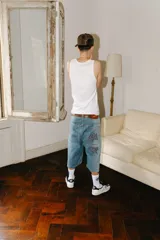 Bermuda de jean de corte baggy, lavado celeste con efecto desgastado. Presenta bordados grandes en los bolsillos traseros con caracteres chinos en negro y blanco. Tiene un parche de cuero marrón en la cintura trasera.