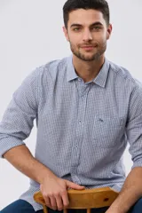 Camisa de lino a cuadros en tonos celeste y blanco, de manga larga, con cuello camisero, cierre frontal con botones y un bolsillo ojal en el pecho con detalle bordado.