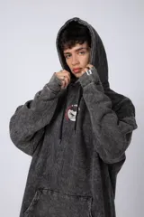 Buzo canguro oversize de algodón friza con efecto de teñido artesanal acid wash en color gris oscuro. Presenta capucha con cordones ajustables, bolsillo frontal tipo canguro y estampa pequeña en el pecho.