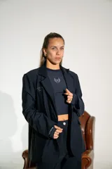 Blazer de lycra color negro, de corte oversize y diseño estructurado con solapas clásicas. Presenta detalles bordados sutiles en la solapa y en el puño de la manga.