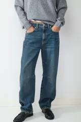 Jean de tiro medio con corte barrel y ajuste relajado, confeccionado en denim de algodón. Presenta diseño clásico de cinco bolsillos, cierre frontal con cremallera y botón metálico.