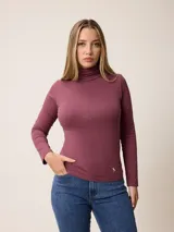 Remera de manga larga con cuello tortuga, confeccionada en algodón con elastano. Presenta un corte ajustado al cuerpo y un pequeño bordado distintivo en la parte inferior.
