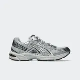 Championes Asics modelo GEL-1130, de estilo retro inspirados en el running de 2008. Presentan un diseño en tonos gris y plateado, con detalles en negro y suela con tecnología GEL en el talón.