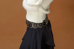 Campera corta de diseño combinado en color marrón. Presenta cuerpo de piel sintética con capucha, mangas tejidas en punto acanalado y cierre frontal con vista de cuero sintético. Incluye detalles de pompones laterales en el ruedo.