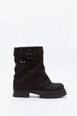 Bota de caña media color negro, con suela robusta dentada y detalle de correa con hebilla y argolla metálica en la parte superior.