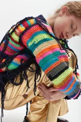 Buzo tejido al crochet con diseño a rayas horizontales multicolores y flecos colgantes.