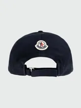 Gorra de baseball Moncler color azul marino, con visera curva y detalle de borde en color crema. Presenta el logo de la marca bordado en la parte frontal en color crema.