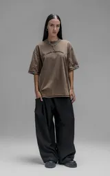 Remera de manga corta con calce oversize, confeccionada en algodón con proceso batik artesanal. Presenta recortes superpuestos y costuras expuestas en el frente, espalda y mangas.