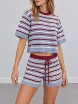 Conjunto de dos piezas confeccionado en tejido de punto a rayas horizontales en tonos celeste, beige y bordó. Incluye una remera de manga corta con cuello redondo y un short con cintura elástica ajustable mediante cordón.