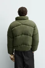 Cazadora acolchada tipo puffer de corte relajado, color verde militar. Presenta cuello subido, cierre frontal con cremallera, bolsillos laterales con cierre y puños elásticos.