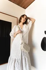 Bandolera de cuero color beige, con correa larga regulable y cierre superior con cremallera.