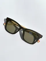 Lentes de sol con armazón bicolor, frente negro y patillas en tono beige con detalle de marca grabado. Cuentan con cristales polarizados con protección UV 400.