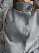 Chaqueta de paño color marrón oscuro, con diseño de doble botonadura frontal y cuello alto estructurado. Presenta mangas largas y un corte recto y holgado.