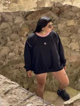 Buzo deportivo de verano (sin felpa) color negro, corte oversize, con cuello redondo y pespuntes contrastantes en color rosa pálido. Presenta una pequeña letra 'K.' bordada en el pecho.