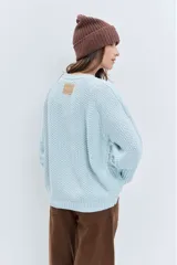 Sweater de punto en color celeste, con diseño de trenzas y textura en relieve. Presenta cuello redondo, mangas largas con puños ajustados y un corte holgado.