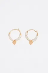 Aretes tipo argolla dorados con perlas irregulares engarzadas y un dije colgante de corazón liso y dorado en la parte inferior.