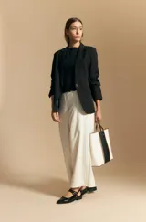 Top sin mangas de jacquard color negro, con cuello cerrado y silueta recta. Presenta una textura trabajada con relieve y una terminación suavemente ondulada en el ruedo.