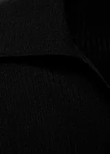 Jersey de canalé color negro, con cuello camisero, manga larga y diseño entallado. Cuenta con detalle de botón efecto joya.