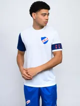 Remera de fútbol blanca con manga derecha azul marino y manga izquierda blanca con una banda azul marino y detalles rojos. Tiene el escudo del Club Nacional de Football en el pecho.