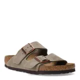 Sandalias Birkenstock modelo Arizona de dos tiras ajustables con hebillas metálicas. Confeccionadas en gamuza color taupe, cuentan con plantilla anatómica de corcho y suela de goma antideslizante.
