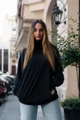 Buzo negro de algodón con cierre parcial en el cuello y bolsillo oculto.