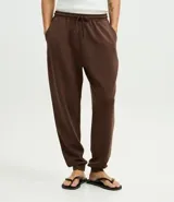 Pantalón jogger de pijama color negro, confeccionado en tejido de modal con mezcla de poliéster y elastano. Presenta cintura elástica con cordón de ajuste, bolsillos laterales y puños ajustados en el ruedo.