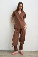Pantalón recto marrón de lino y algodón, con tiras regulables en los tobillos para ajustar.