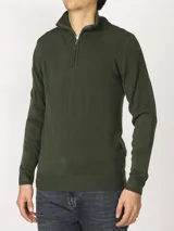 Sweater verde oliva de tejido acrílico con textura similar al cashmere, corte clásico, cuello alto con cierre metálico y tirador de cuerina ecológica.