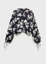 Blusa de manga larga con estampado floral en blanco y negro, cuello redondo y puños elásticos con lazos.