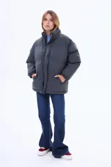 Campera puffer de corte holgado, color negro, con cuello alto, cierre frontal y puños elásticos.