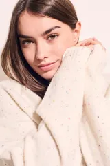 Sweater color crema con motas de colores, de corte oversize, cuello redondo y mangas largas.