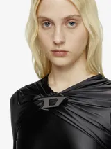 Vestido largo negro de manga larga y cuello drapeado, con broche metálico en forma de 'D' en el escote. El vestido tiene un corte al cuerpo en la parte superior y cae en una falda fluida.