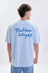 Remera de manga corta con corte oversize, color celeste, con estampa en la espalda que dice 'Italian Delight' en color azul.