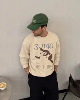 Buzo de cuello redondo color beige, con diseño gráfico en el frente que incluye la leyenda 'Sumo', una ilustración de un luchador de sumo y listado de canciones.