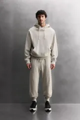 Sudadera con capucha color gris claro, de corte holgado, con bolsillo tipo canguro y cordones ajustables.