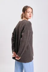 Cardigan de punto en color marrón con escote en V, cierre frontal con botones grandes y mangas largas. Presenta puños y ruedo acanalados.
